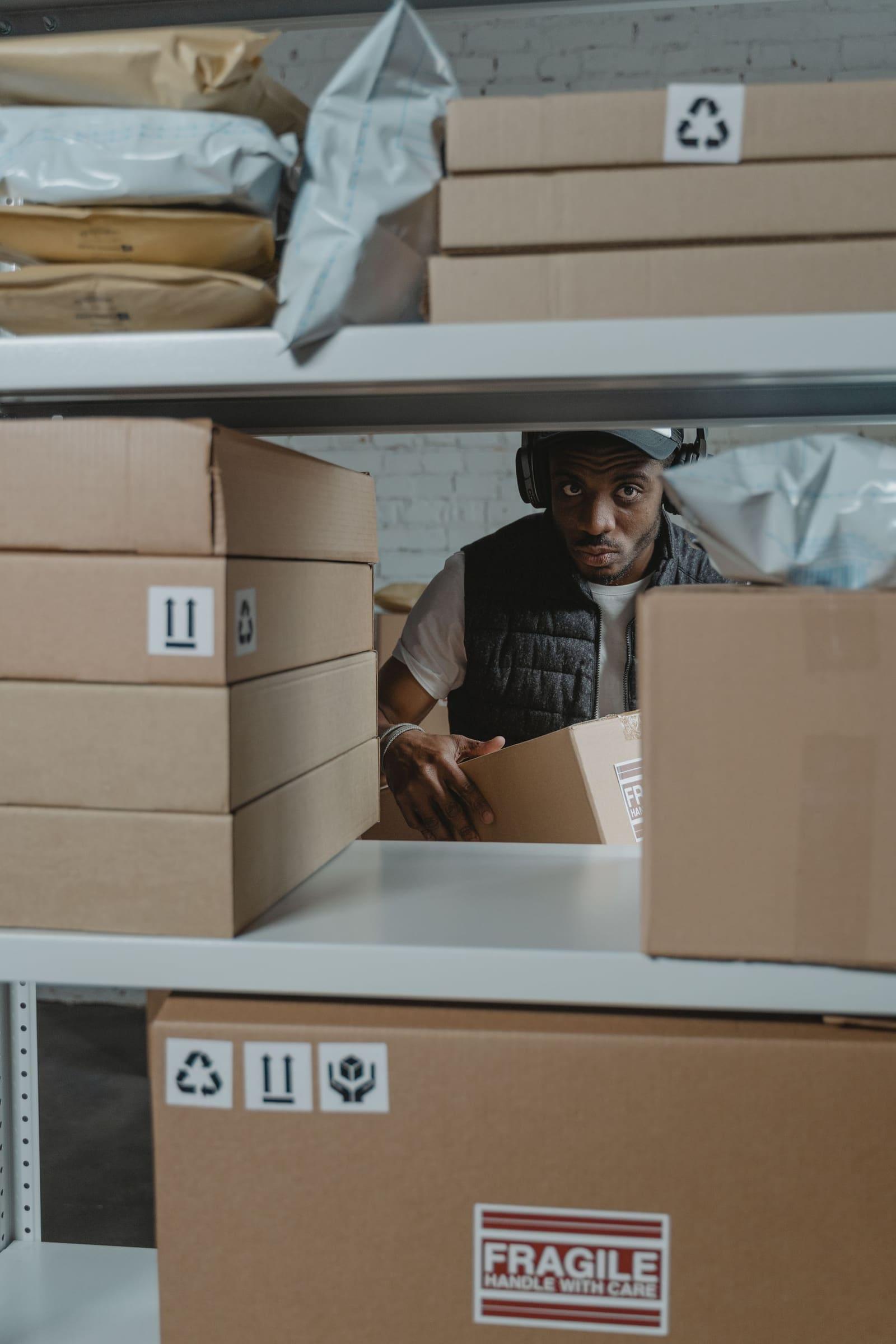 A fulfilment operative organising cartons and packages on warehouse shelving.